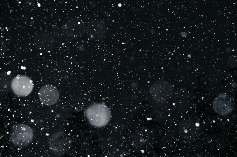 Snow falling heavily at night against a dark sky with blurred bokeh lights