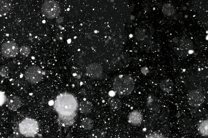 Snow falling heavily at night against a dark sky