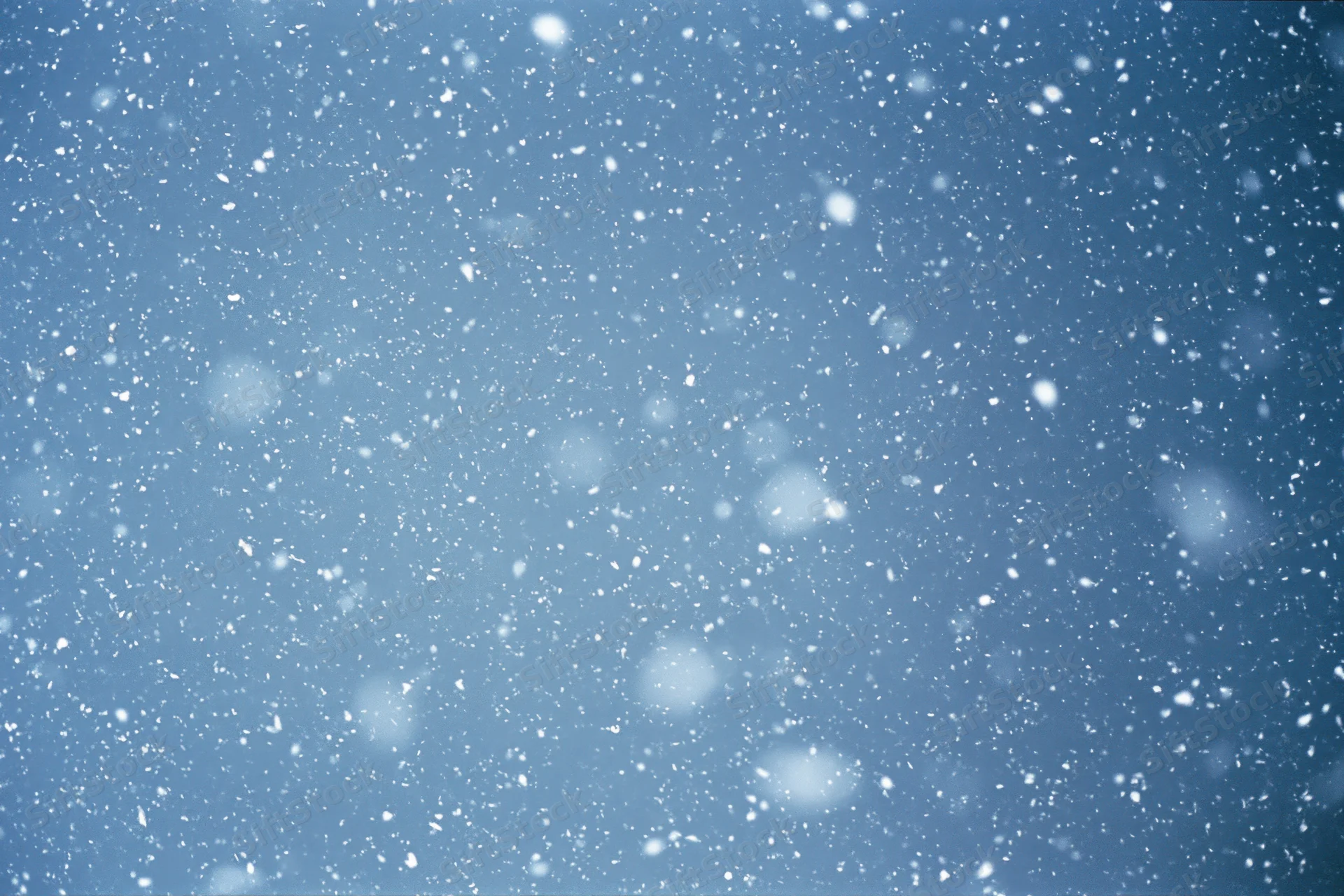 Snowflakes falling mid-air against a clear winter sky