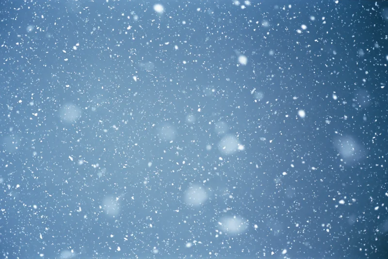 Snowflakes falling mid-air against a clear winter sky