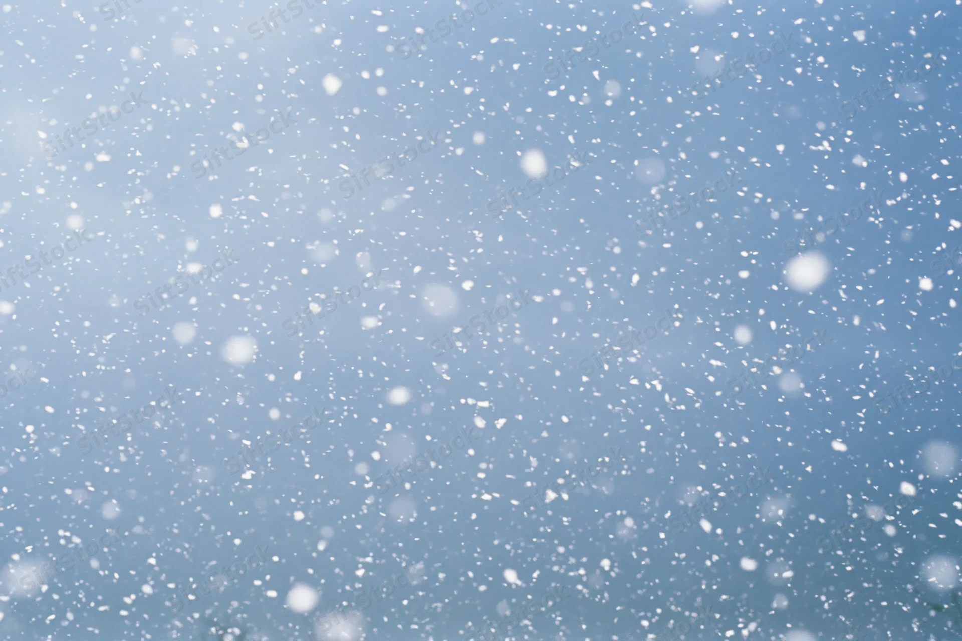 Snowflakes falling through a blue winter sky