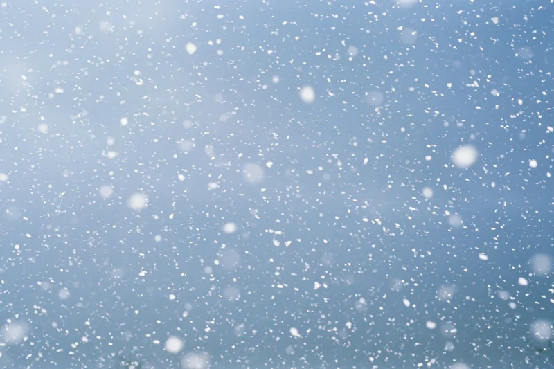 Snowflakes falling through a blue winter sky