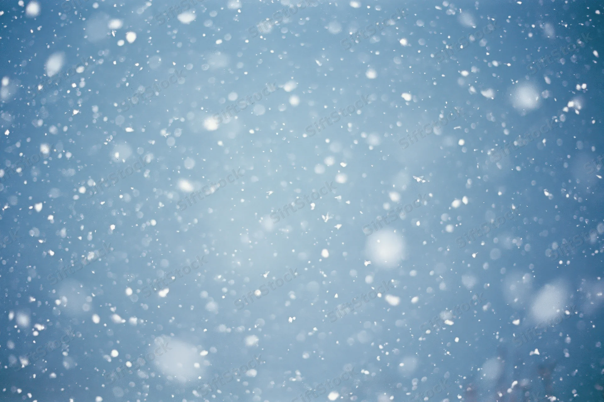 Snow falling through a clear blue winter sky