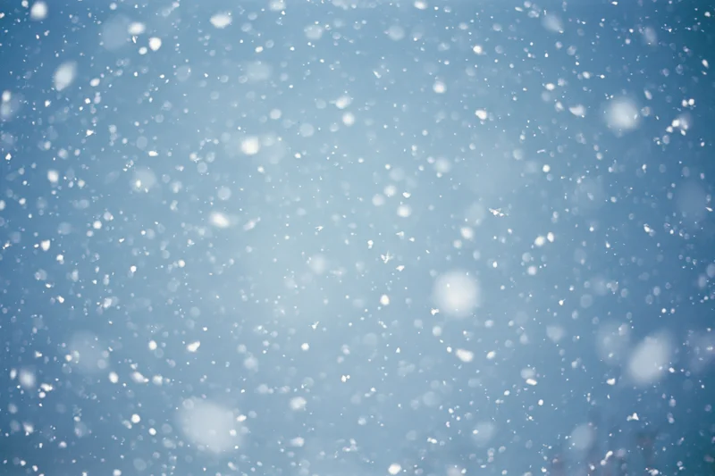 Snow falling through a clear blue winter sky