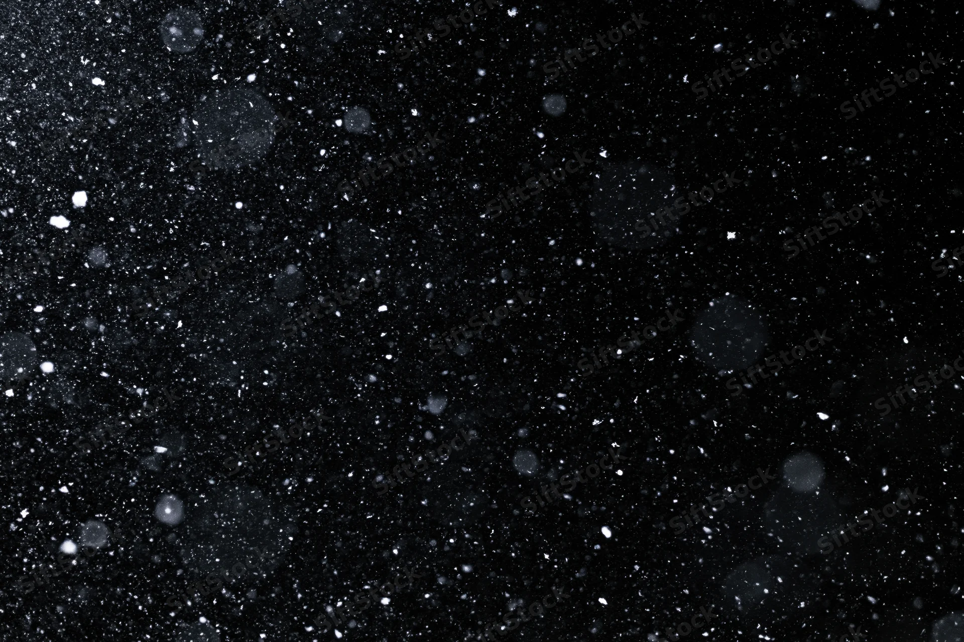 Snow falling against a black night sky