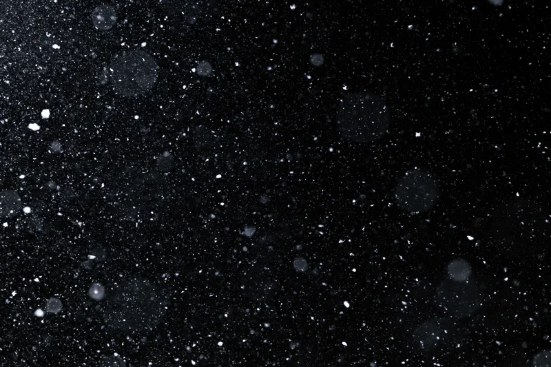 Snow falling against a black night sky