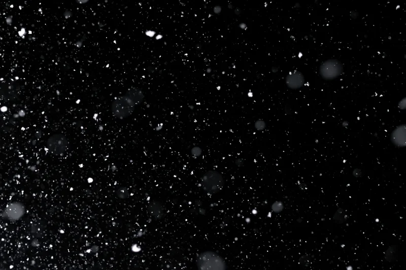 Snow falling against a black night sky