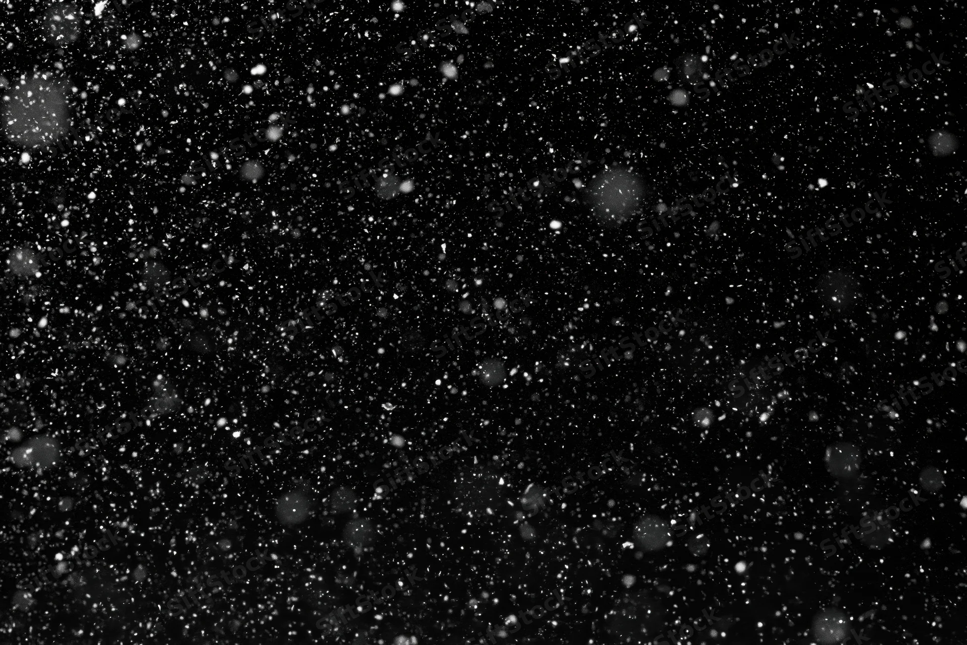 Snow falling densely against a black night sky