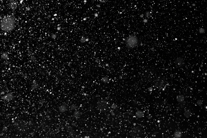 Snow falling densely against a black night sky