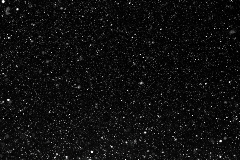 Heavy snowfall falling against a pure black night sky