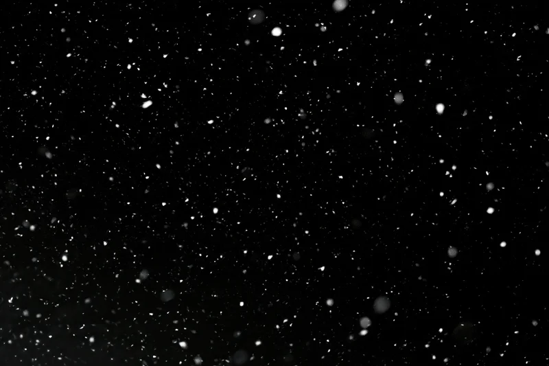 Snow falling against a black night sky