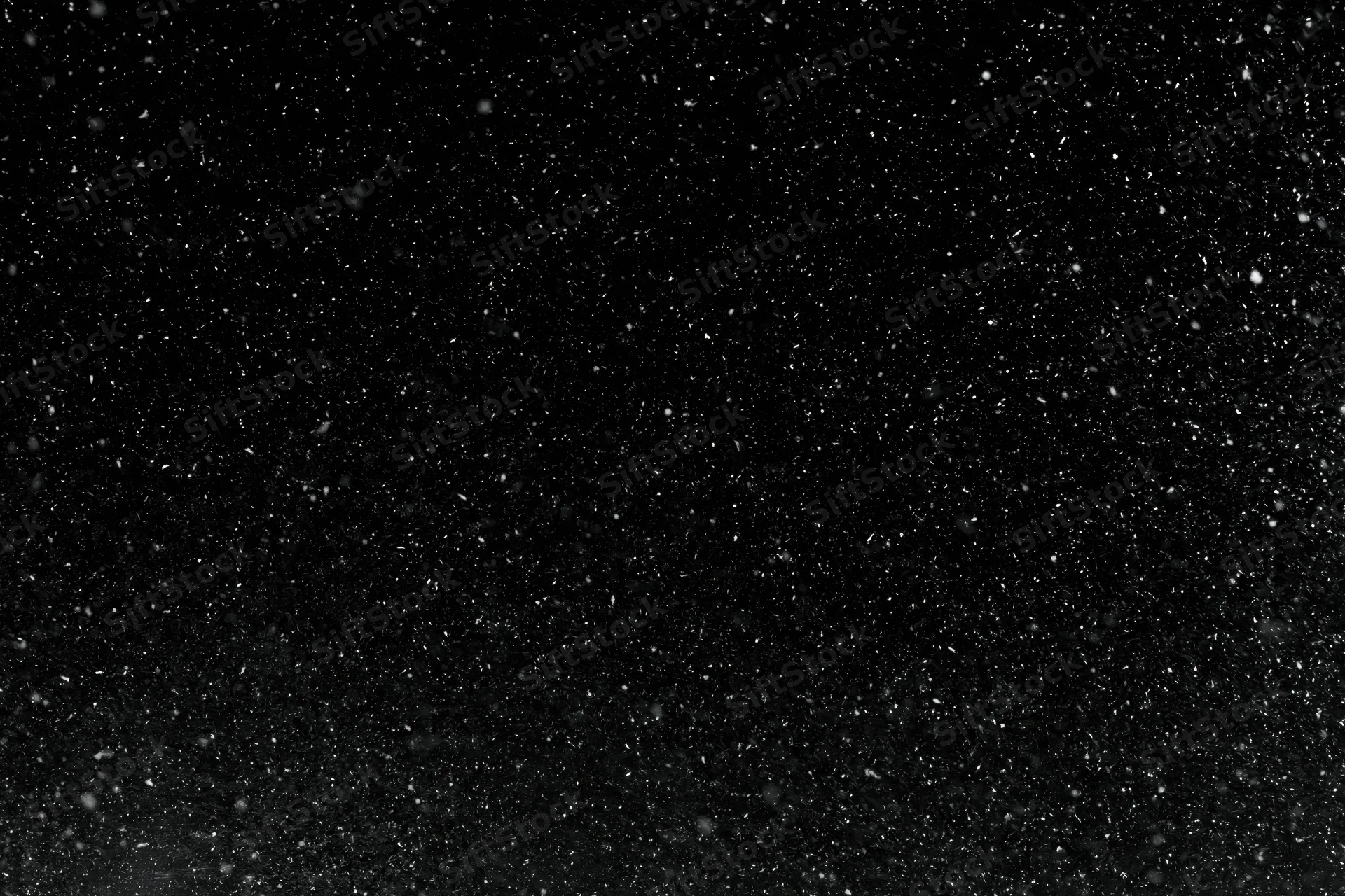 Heavy snowfall falling against a black night sky