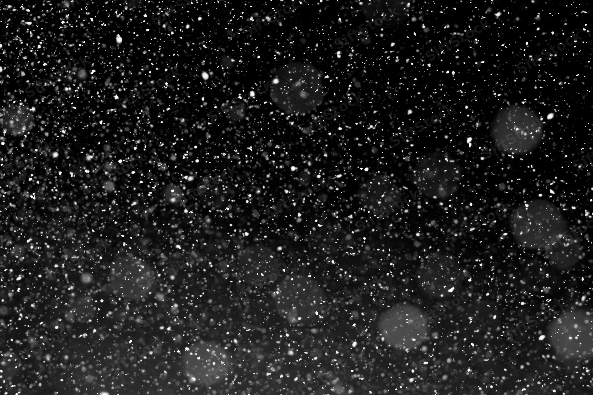 Snow falling against a black night sky
