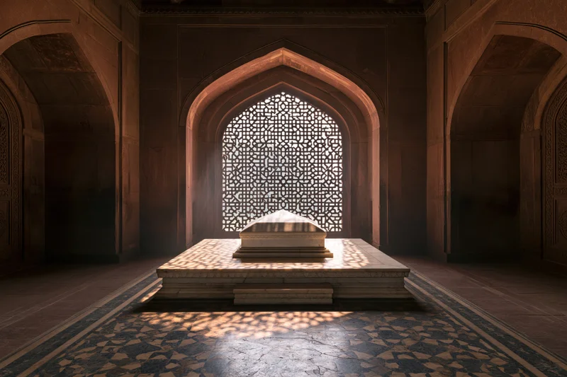 White marble sarcophagus on raised platform in arched chamber with lattice window casting light patterns on floor