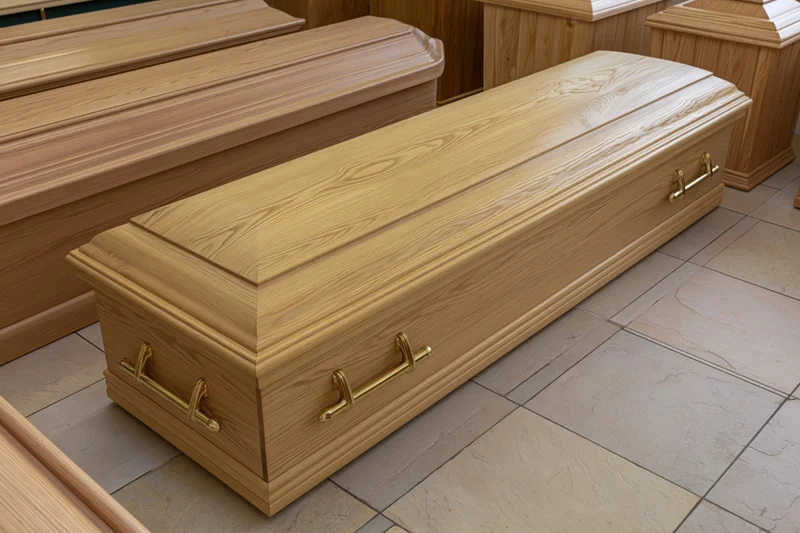 Wooden coffin with brass handles displayed in a funeral home showroom