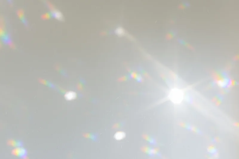Light refractions scattered across a plain white-grey wall surface