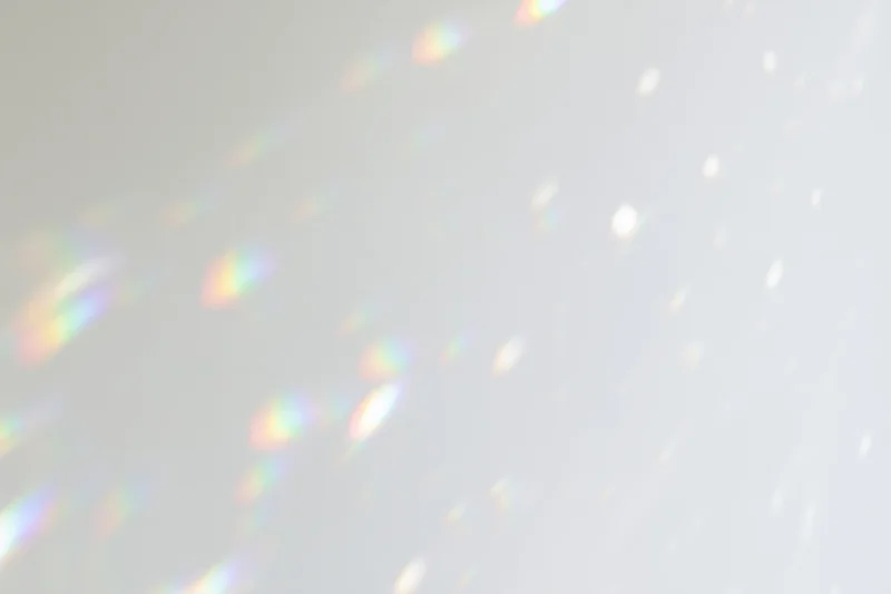 Light refractions scattered across a plain white-grey wall