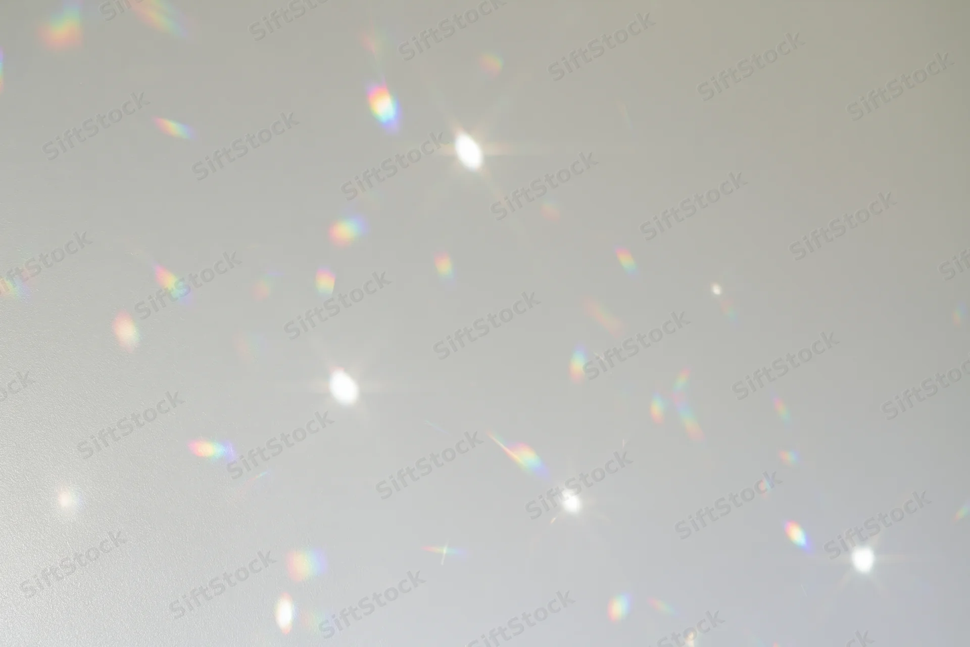 Light refractions scattered across a plain white-grey wall surface