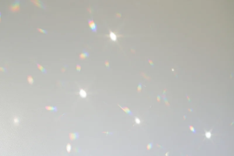 Light refractions scattered across a plain white-grey wall surface