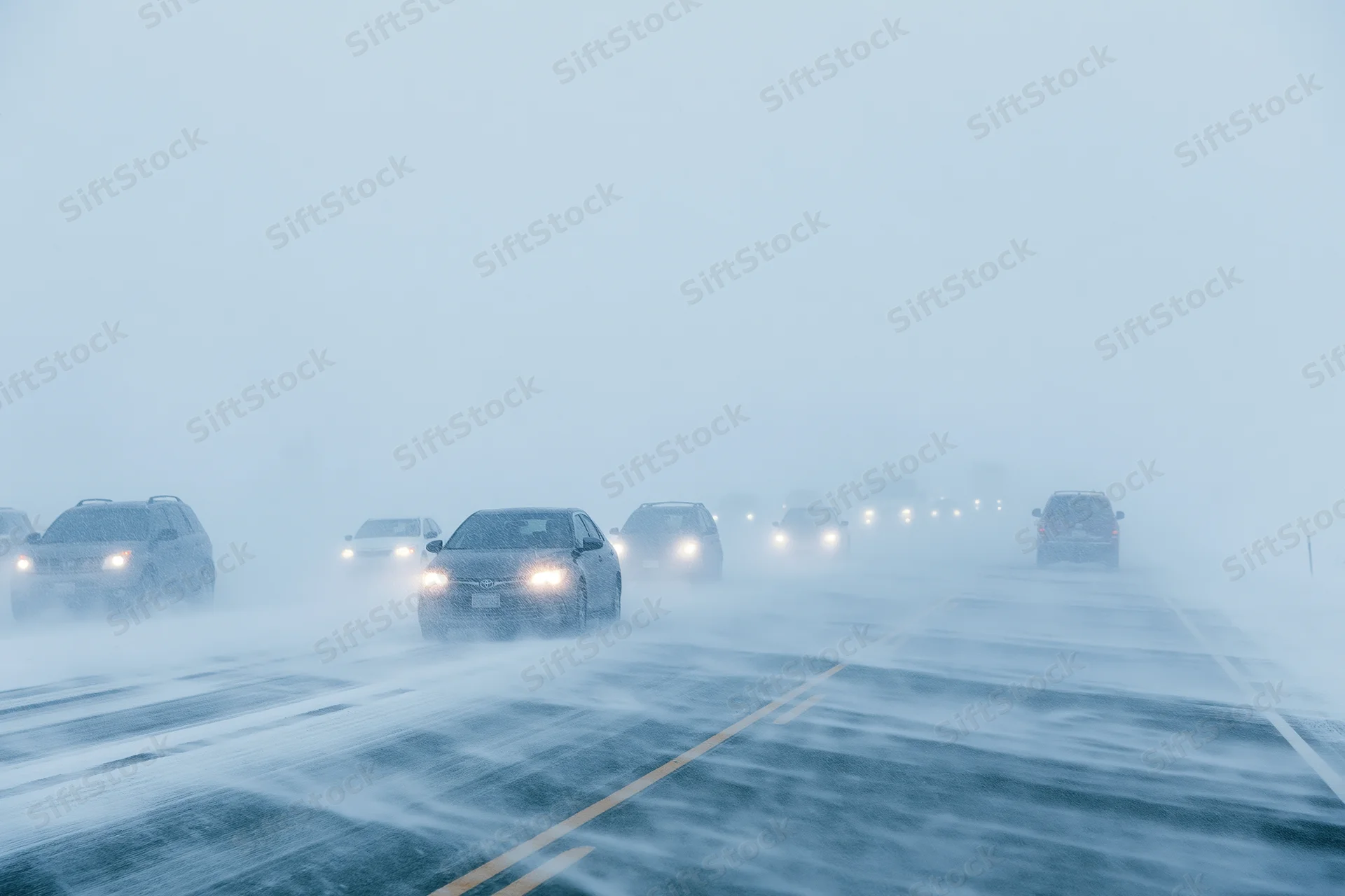 Cars driving on a multi-lane highway during a heavy snowstorm