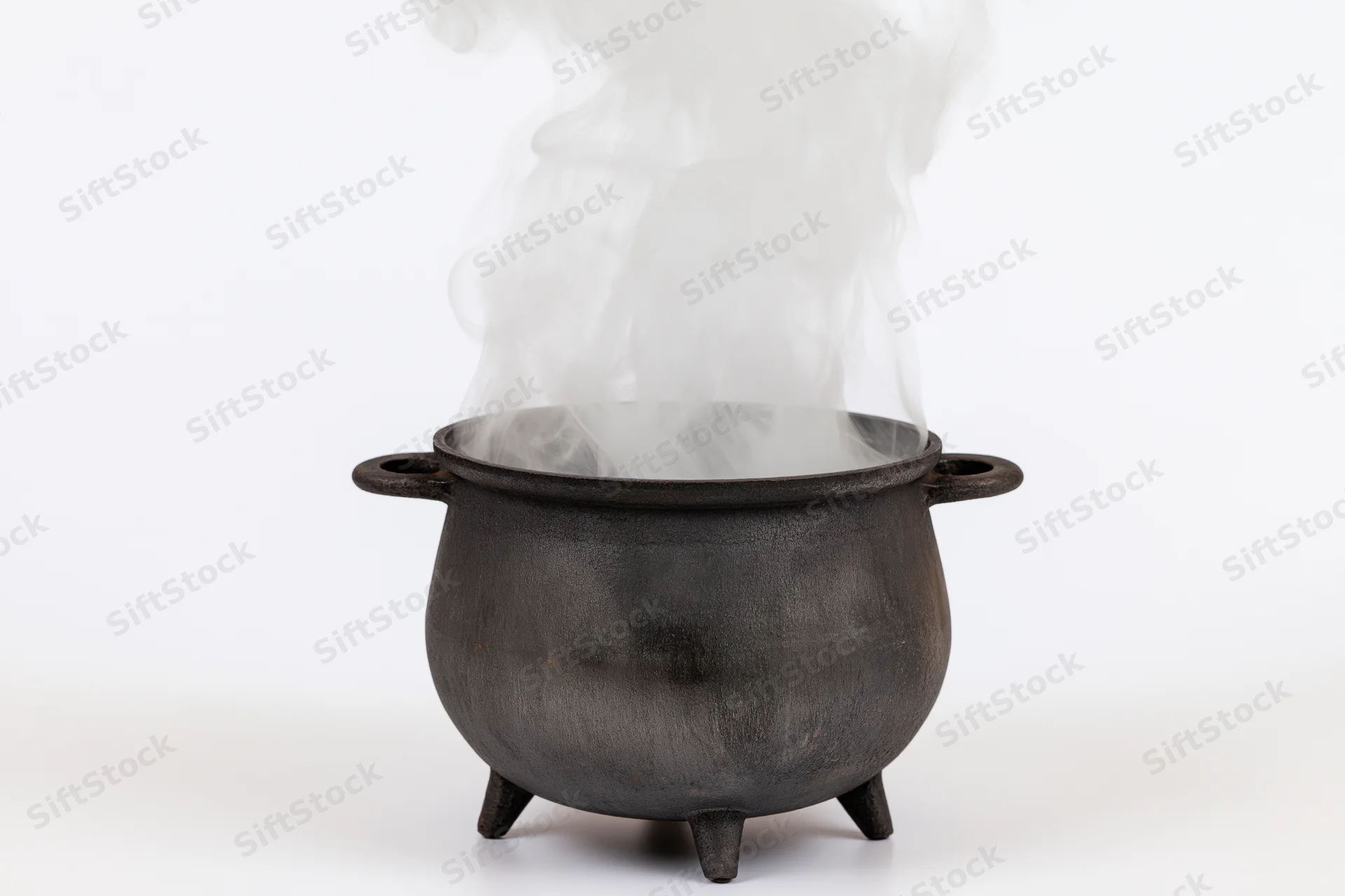 Black cast iron cauldron steaming with white smoke on white background