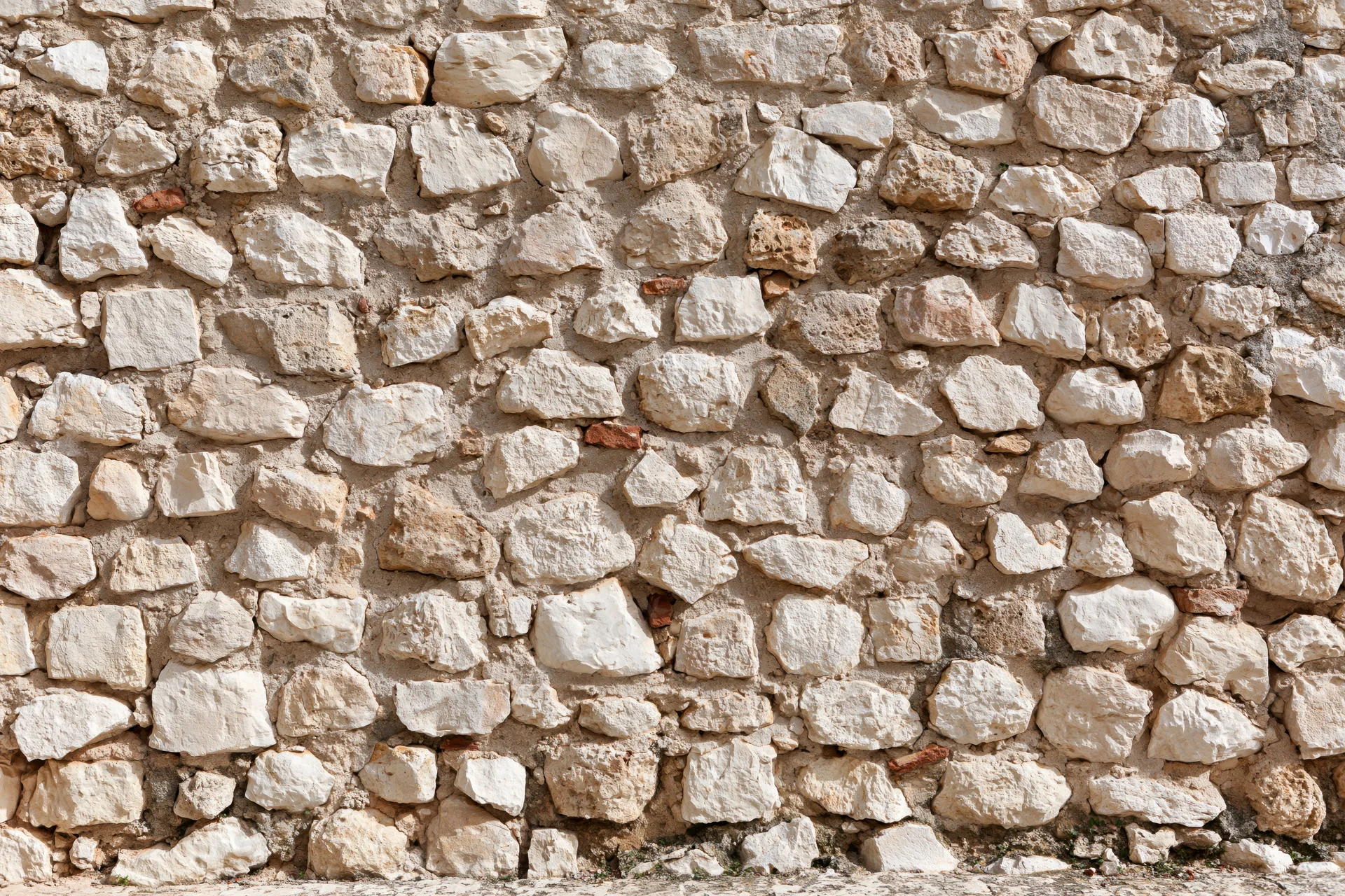 Close-up of an old irregular stone wall with weathered texture and mortar filling the frame