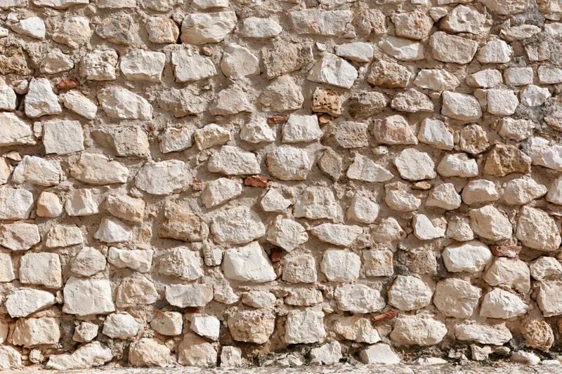Close-up of an old irregular stone wall with weathered texture and mortar filling the frame