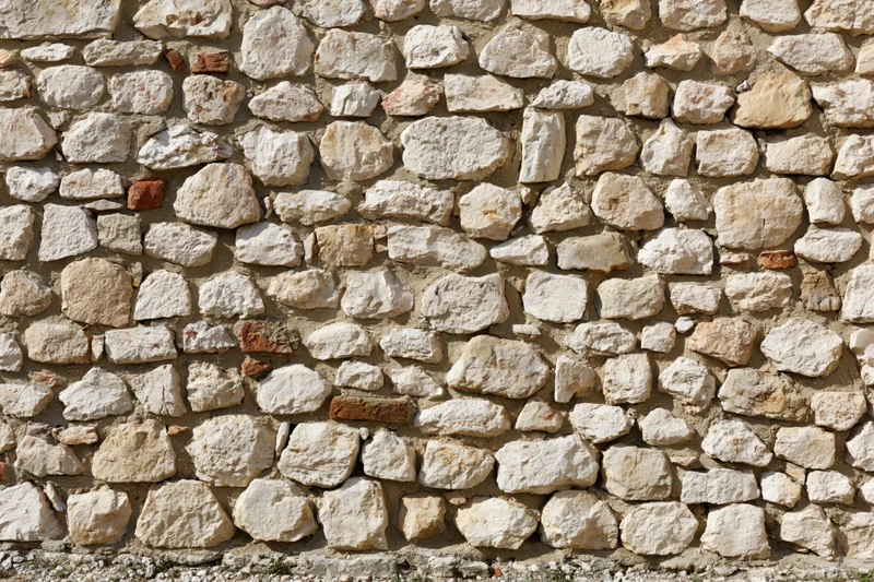 Close-up of an old irregular stone wall made of limestone and brick with mortar filling the frame