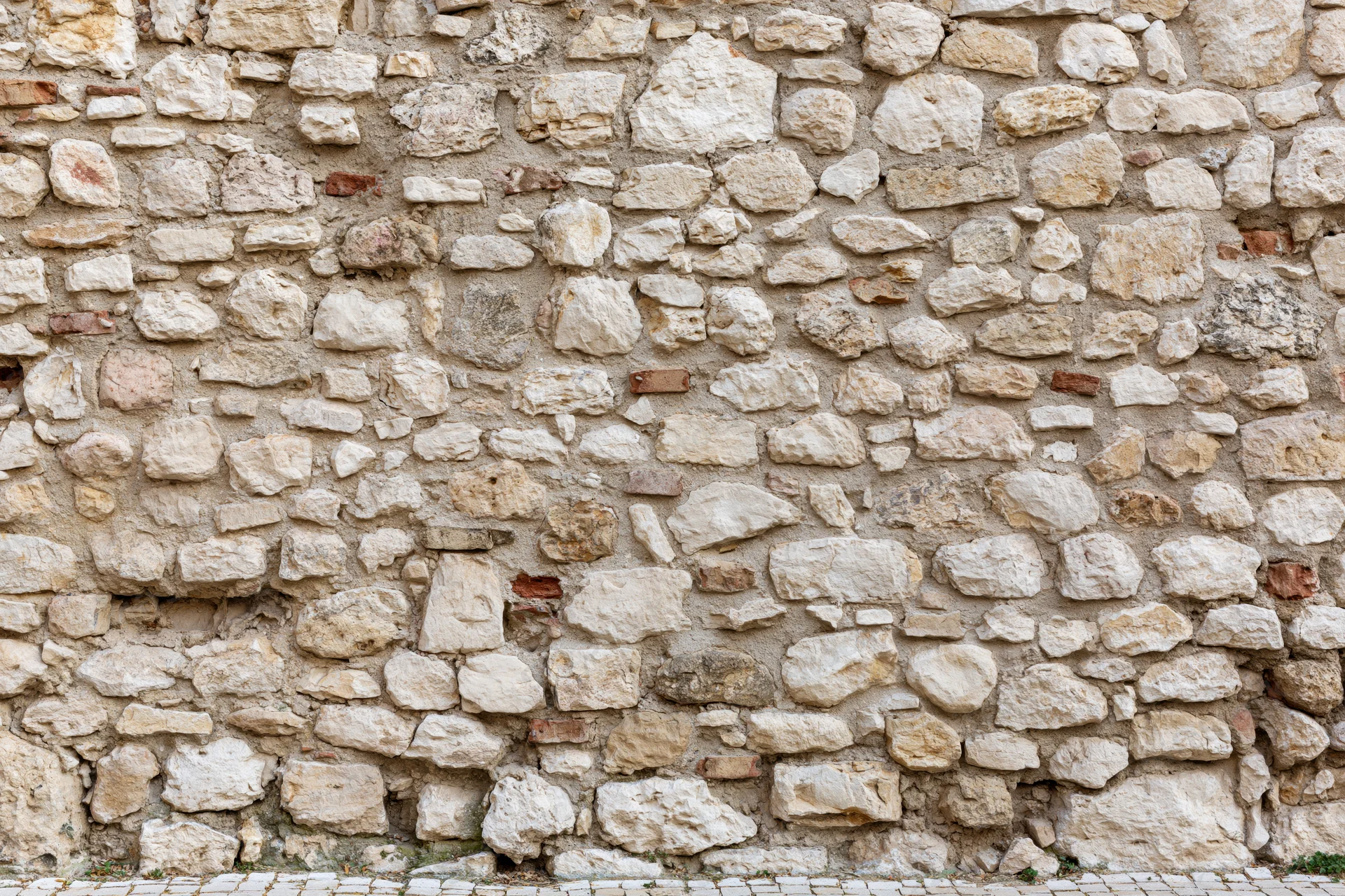 Old irregular stone wall with weathered texture and mortar filling the frame