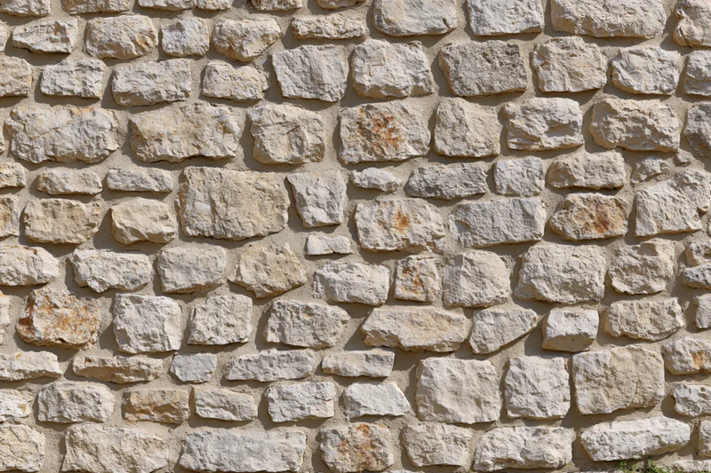 Close-up of an old rustic stone wall with uneven natural stones and mortar filling the frame