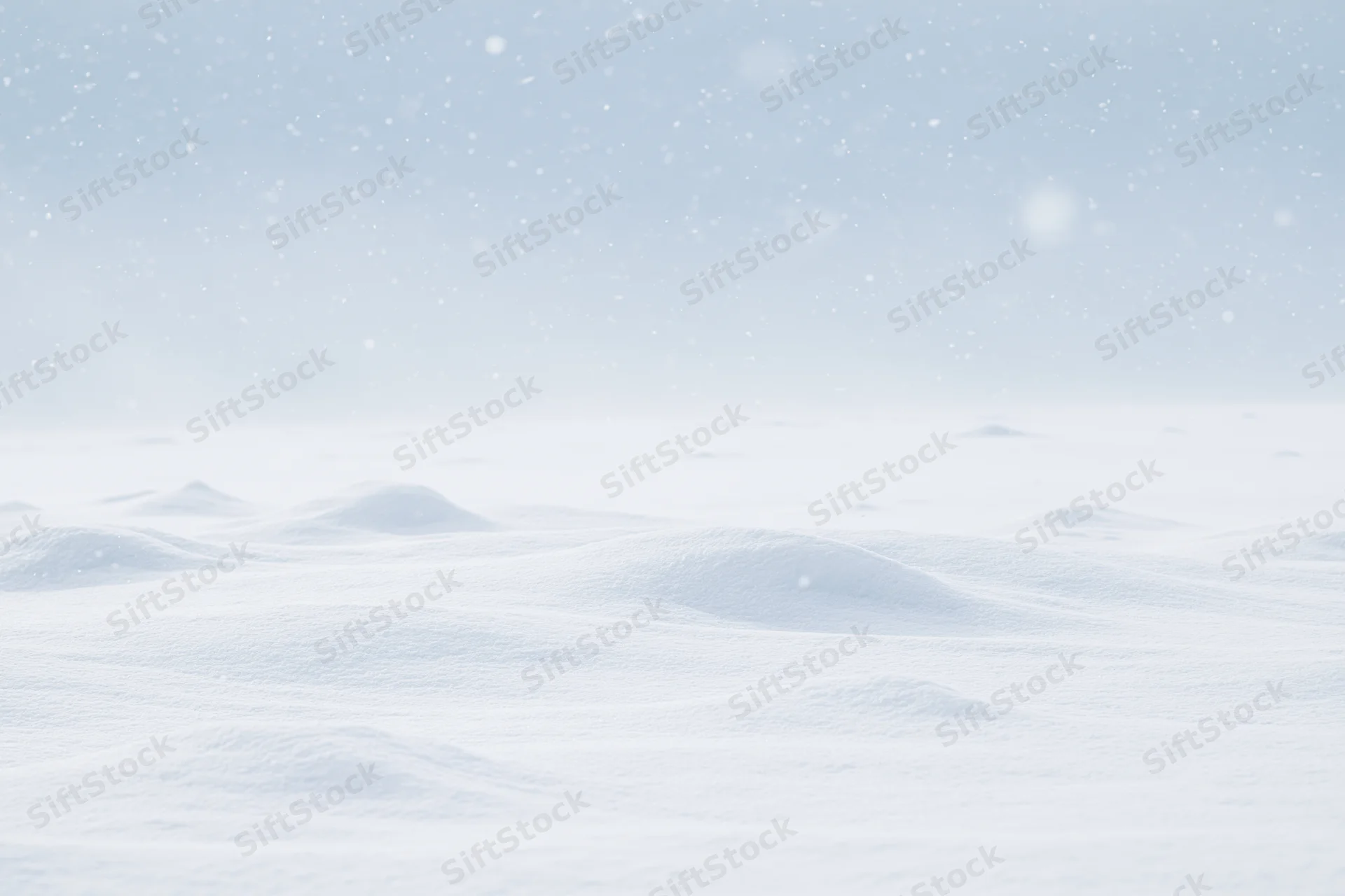 Snow-covered field under falling snow with soft undulations and overcast sky