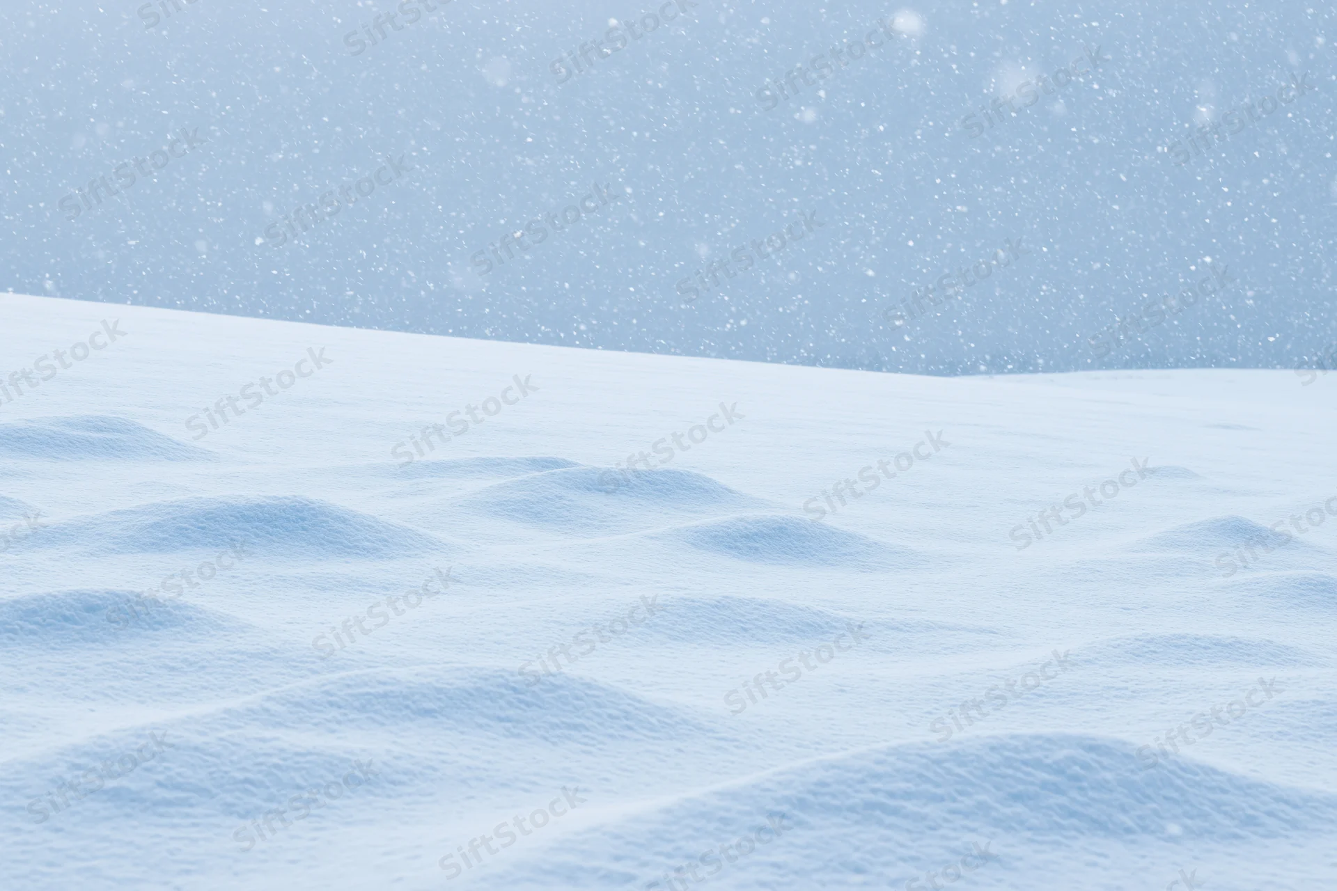 Snow-covered field under heavy snowfall with soft drifts and overcast sky