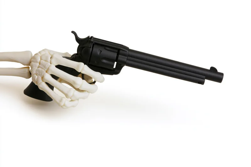 Skeleton hand gripping a black revolver on white background