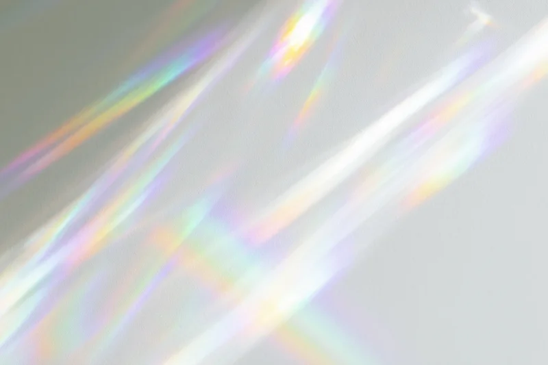 Prismatic light streaks scattered across a soft white surface