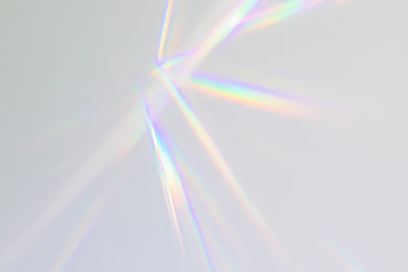 Prismatic light streaks radiating across a soft white background
