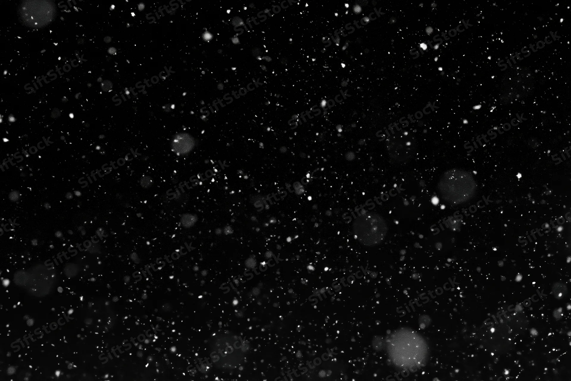 Snowflakes falling against a black night sky