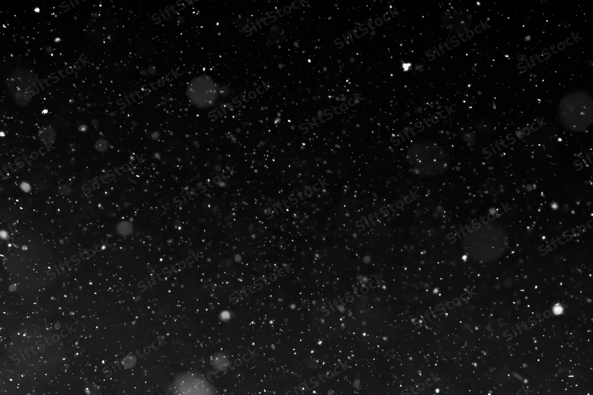 Snowflakes falling against a black night sky