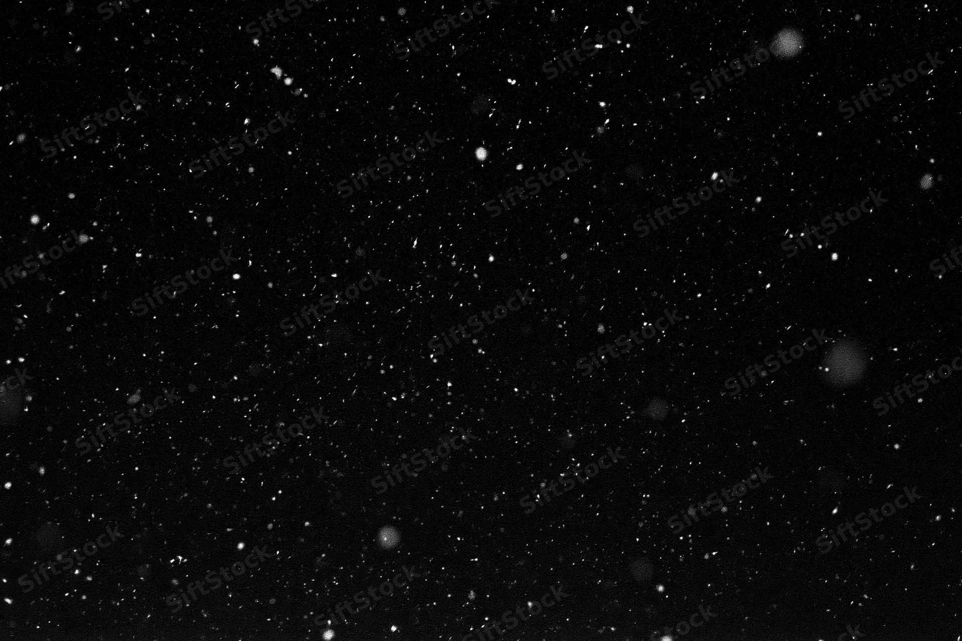 Snowflakes falling against a black night sky