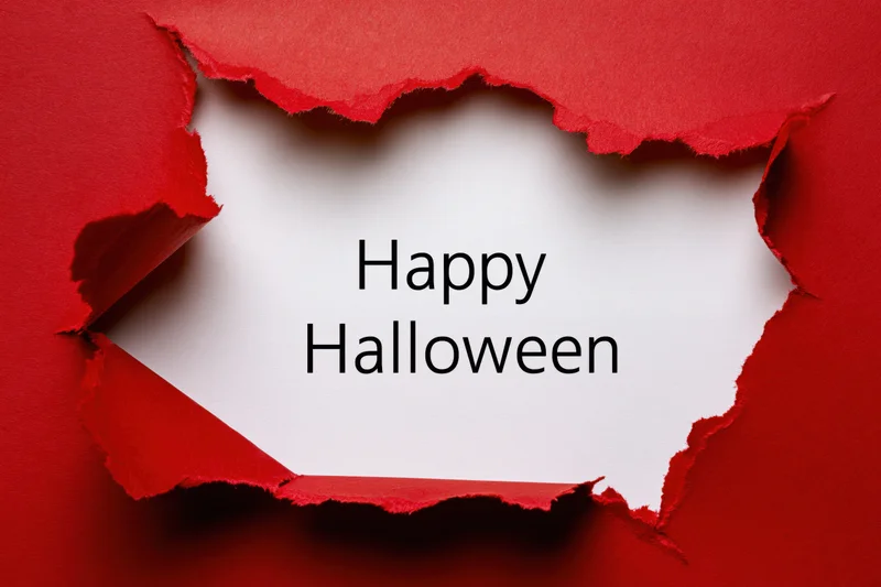 Torn red paper revealing white sheet with happy halloween text