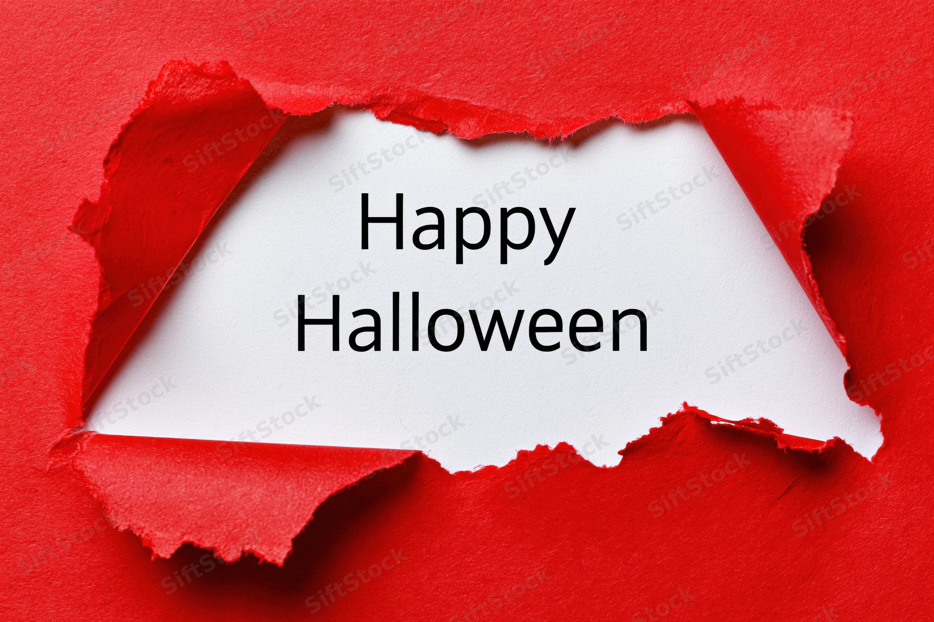 Torn red paper revealing white sheet with happy halloween text