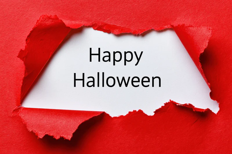 Torn red paper revealing white sheet with happy halloween text