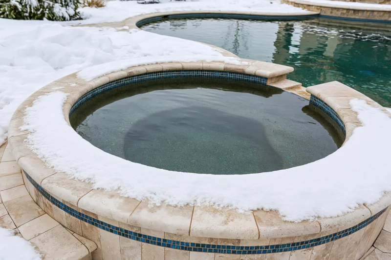 Snow-covered hot tub and swimming pool in a residential backyard