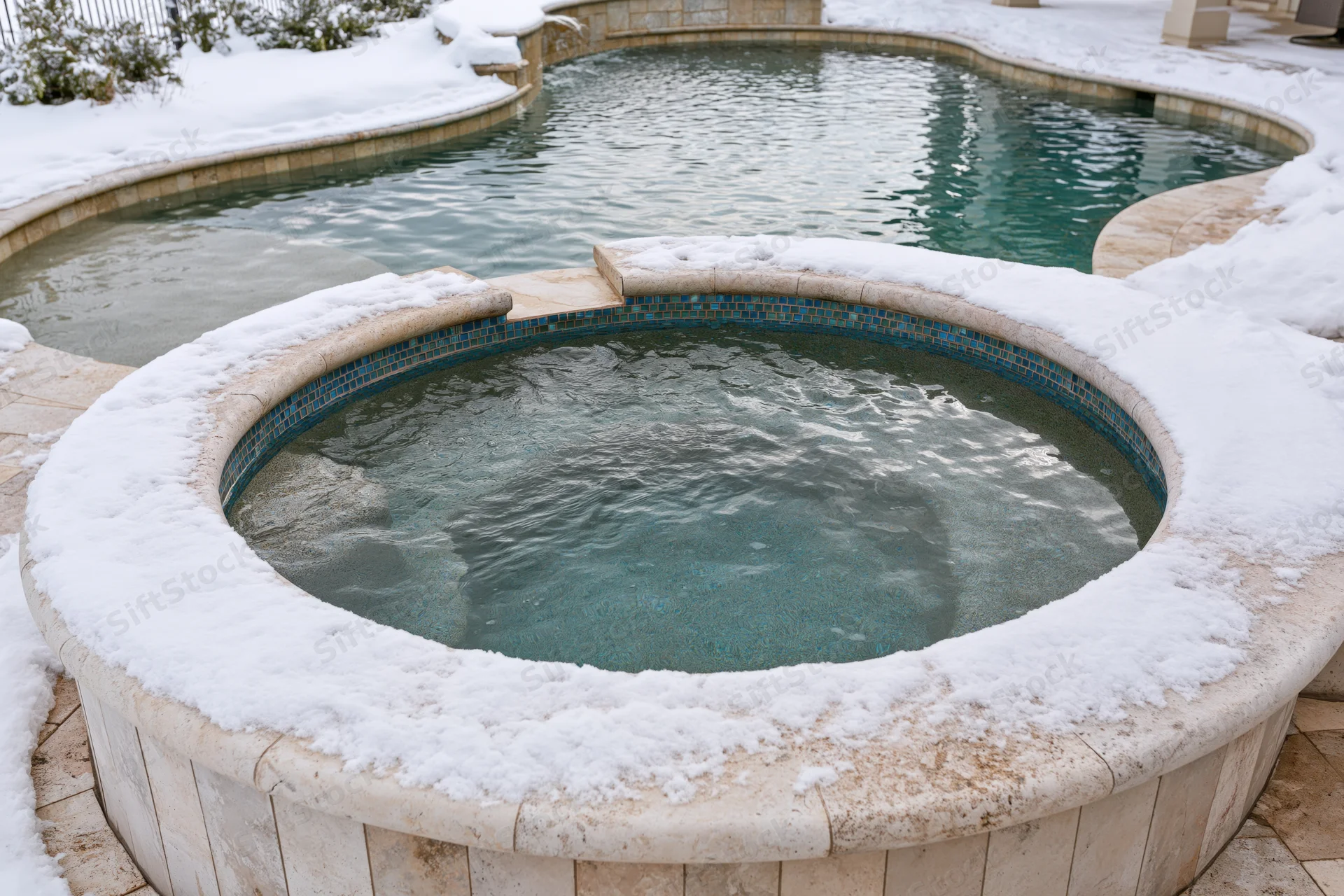 Snow-covered hot tub and swimming pool in a residential backyard