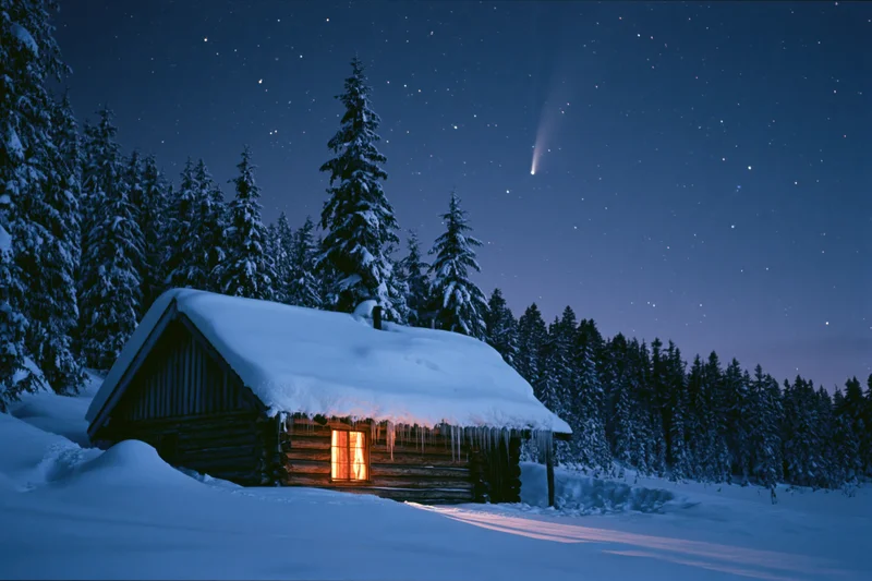 Rustic wooden cabin with glowing window light in snowy forest at night under starry sky with comet