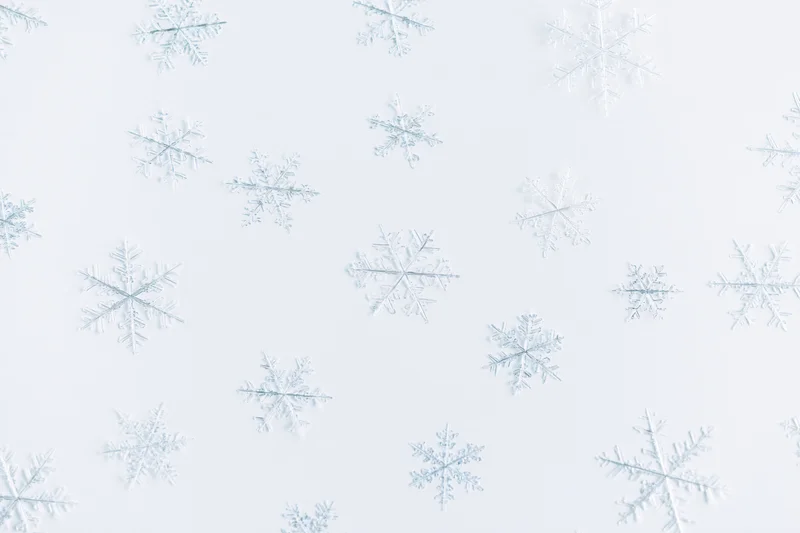 Scattered snowflakes floating against a light white background