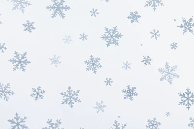 Scattered snowflakes of varying sizes floating against a white background