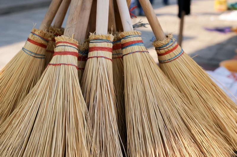 Handmade straw brooms bundled together for display outdoors