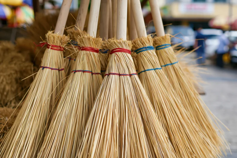 Handmade straw brooms bundled together for display at an outdoor market