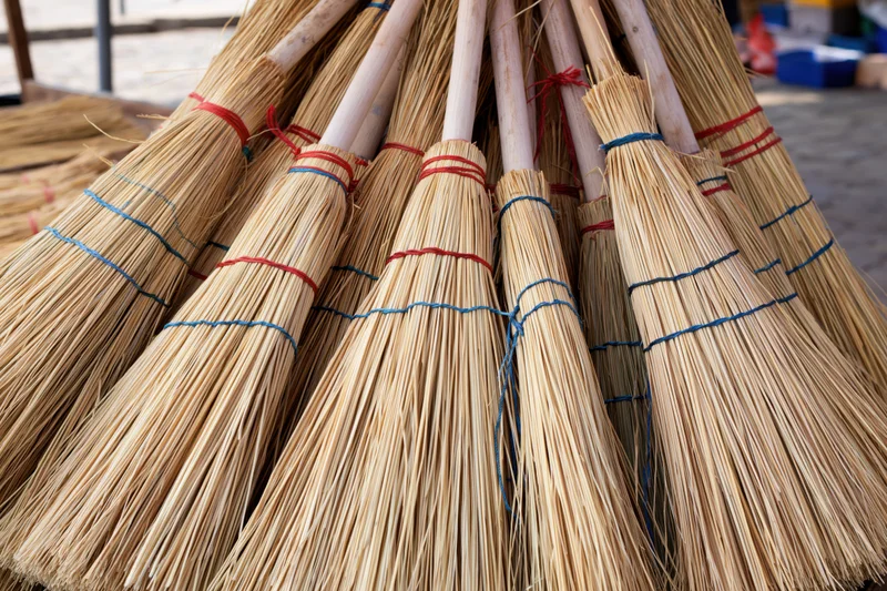 Handmade straw brooms bundled together for display outdoors