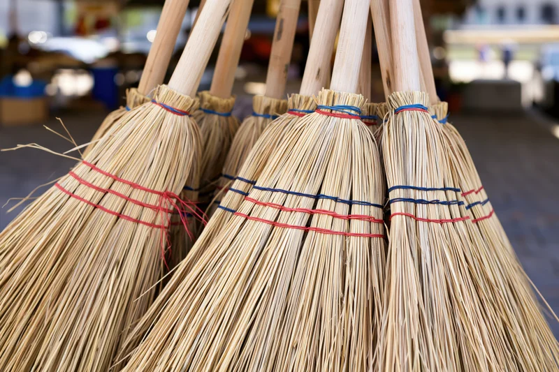 Handmade straw brooms bundled together for display at a market